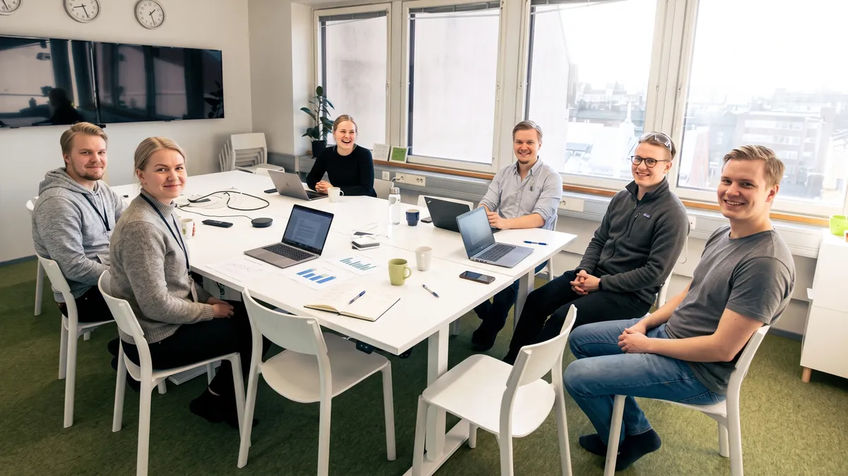 The founding working group of the society — six people around a white meeting table in the Helsinki office, laughing during a planning session